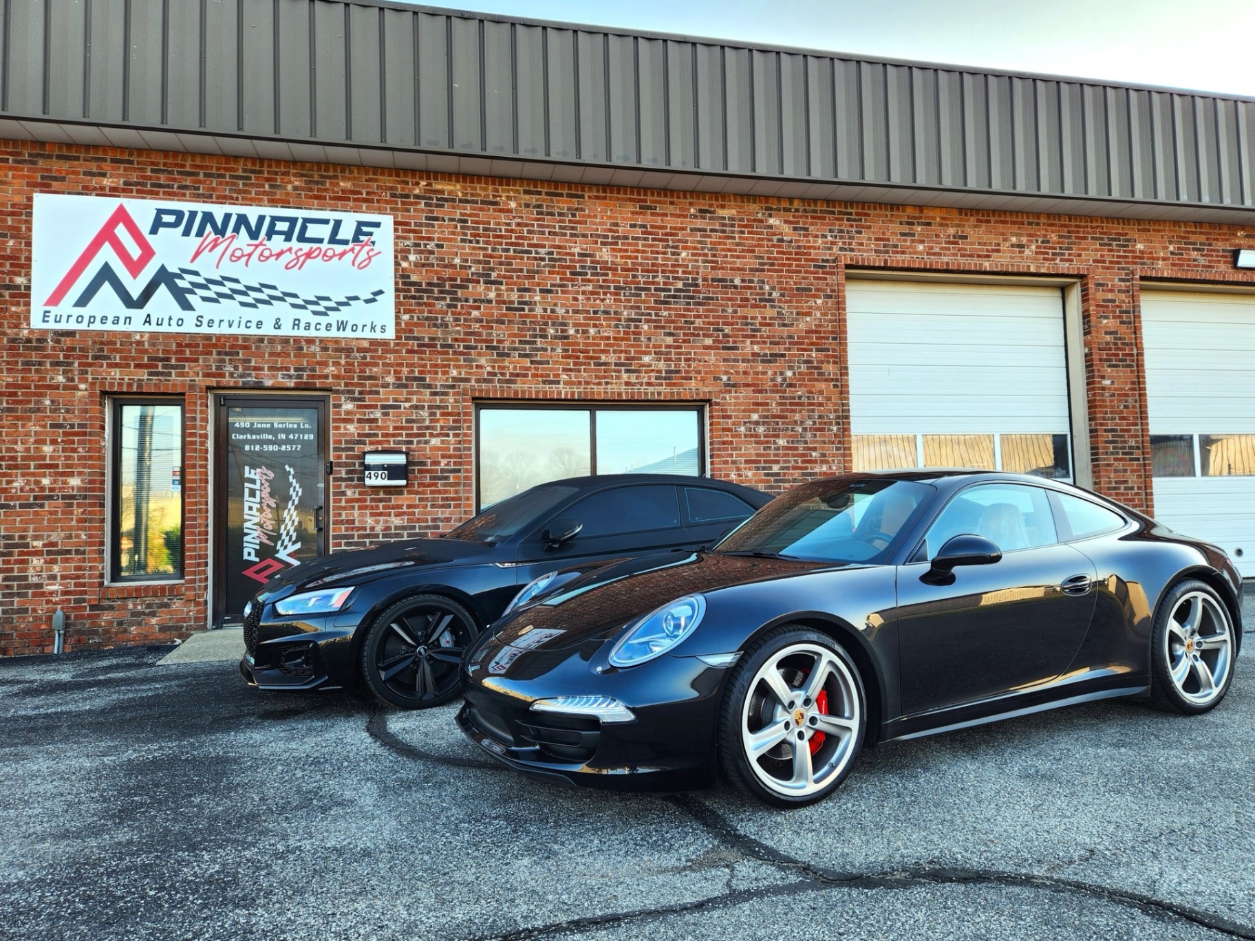 Black Porsche 911 and Audi RS5 at the shop entrance